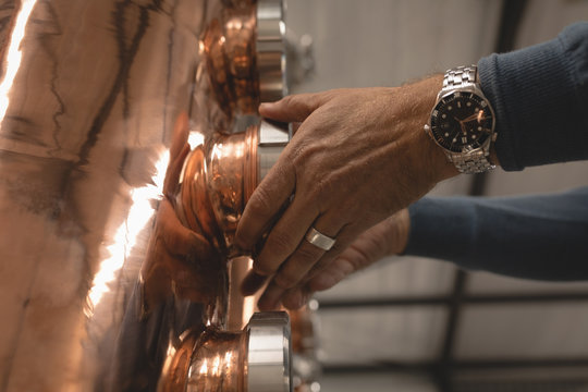 Male worker checking machine of distillery