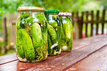 Homemade marinated cucumbers in glass jars on the table.