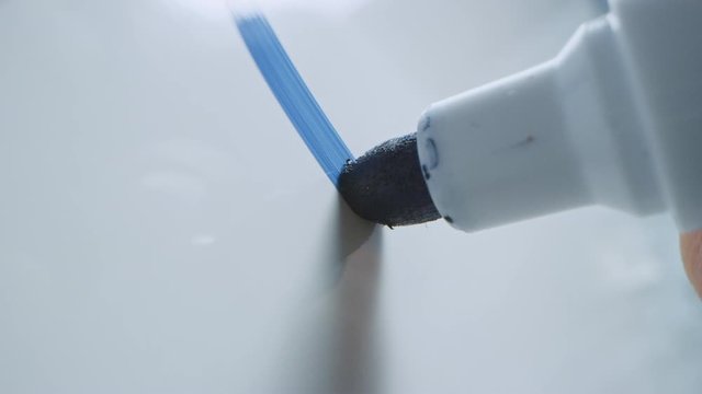 Macro Follow Shot of a Blue Marker Pen Being Held with a Hand. Person Writing on a Whiteboard with Graphs and Business Plans. Pencil is Connected to the Camera. Gripped Shot. Sketching with Fineliner.