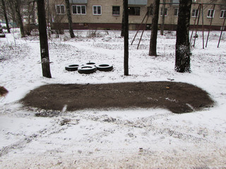 Parking space in winter with snow melted under the car in the yard. Car tires are in the yard.