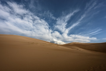 Fototapeta na wymiar Large Cloud Rises Over Sand Dunes