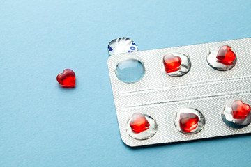 Love pills. Blister pack with red heart shaped pills. Tablets for lovers or potency. Blue background