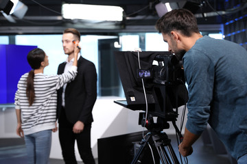 Presenter, makeup artist and video camera operator working in studio. News broadcasting