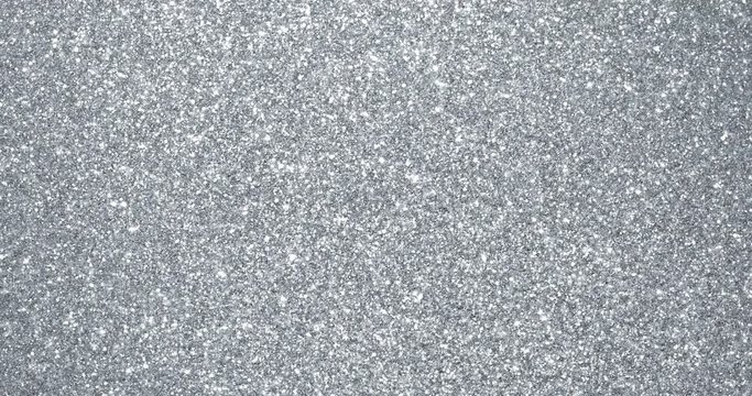 Silver glitter background with sparkling texture. Silver shimmering light, stars sequins sparks and glittering glow foil background