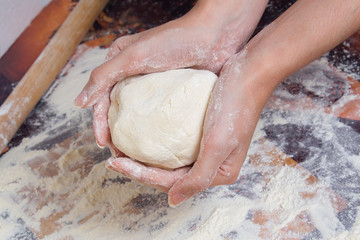 Woman preparing dough from flour. Female hands holding a piece of raw dough.