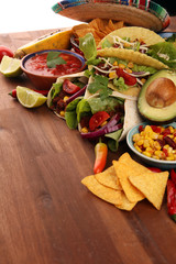 Mexican food, including tacos, guacamole, nachos and pepper on rustic table