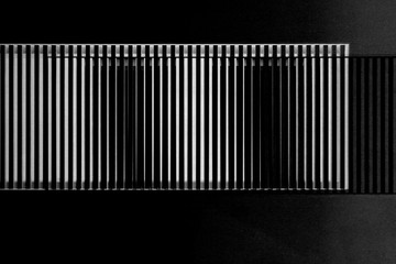 Fototapeta premium Lath structures as pattern with irregular or gently chaotic stripes resembling bar code or business architecture fragment. Abstract geometric template against black background.