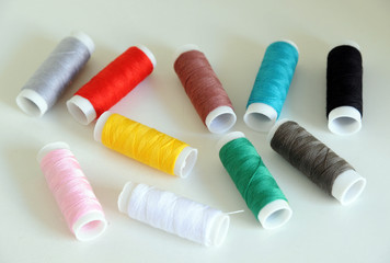 Accessories for tailoring on white table - Scissor , scissors, buttons, needle and thread, spools of colored threads