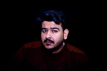 An upset young boy thinking deep in a dark room