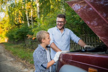 Ojciec uczy syna, jak sprawdzać olej w samochodzie rodzinnym. - 310192946