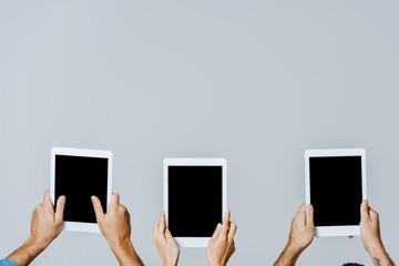 cropped view of young friends holding digital tablets with blank screens isolated on grey