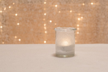 teelichtglas mit leuchtendem teelicht selbstgemacht diy mit salz vor bokeh querformat