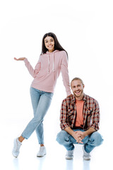 Fototapeta premium full length view of happy african american girl pointing with hand near boyfriend sitting isolated on white
