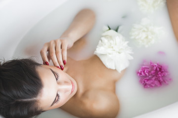 Obraz na płótnie Canvas Perfect woman bathing with flowers and milk