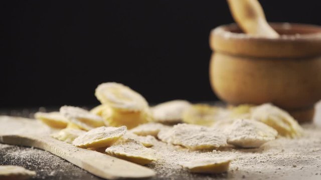 Tasty raw ravioli with flour and basil on wood table