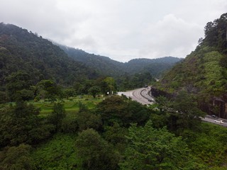 Fototapeta na wymiar Scenic aerial view of “Lebuhraya Utara-Selatan”, a highway located in Malaysia. Highway surrounded by forest, winding road