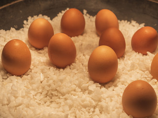 Chicken eggs are placed in a tray filled with salt and a beautiful orange light. Make it look yummy