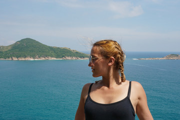 The girl posing on the rock near the blue ocean