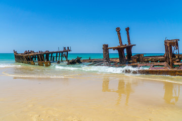 on the beach of fraser island lies the skeleton of a washed-up shipwreck in fine weather