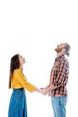 side view of young couple in casual outfit holding hands and looking up isolated on white