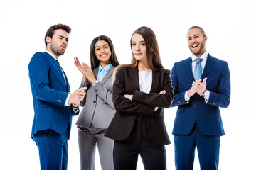 selective focus of happy multicultural business people in suits applauding confident businesswoman in front isolated on white