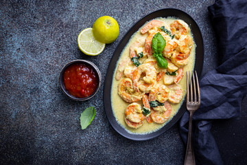 Shrimps in cream sauce with Coconut milk on a plate over black background, top view or view from above, flat lay