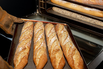 Taking out of the oven, trays of freshly baked bread in a bakery in Madrid, Spain