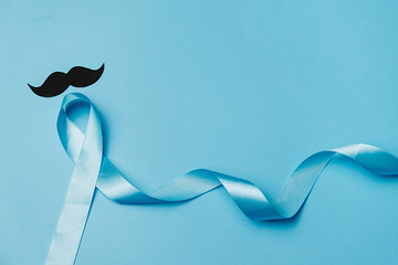 Top view on Light blue ribbon with mustache on blue background. Prostate Cancer Awareness, Movember...
