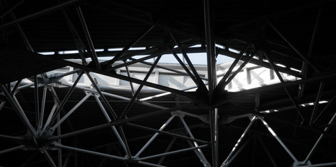 Close-up of industrial building interior fragment. Louvered metal surface and ceiling framework. Grunge abstract modern architecture image. Geometric structure of parallel and intersecting lines.