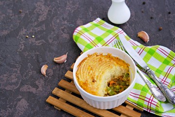 Portion shepherds pie or traditional British potato casserole with minced meat and vegetables on a dark brown concrete background. Potato Recipes. Copyspace.