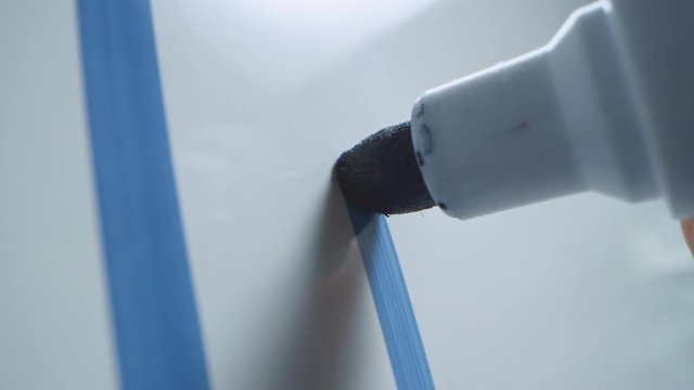 Macro Follow Shot of a Blue Marker Pen Being Held with a Hand. Person Drawing a Circle Around the Word "Plan" on a Whiteboard with Graphs. Pencil is Connected to the Camera. Gripped Shot.