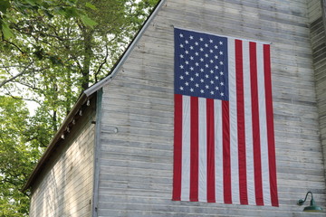Old weathered wooden historic barn with American flag © Alex