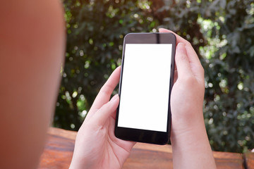 Mockup picture of business woman’s hands holding smart phone with white blank screen in modern place.