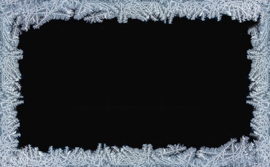 Decorative ice crystals on a window in form of a frame on black matte backgroundP