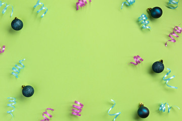 Christmas, New Year, winter concept. Colorful serpentine and balls, on green  background. Flat lay, top view, copy space.