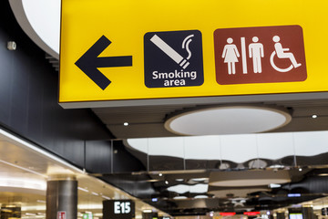 Yellow board with smoking area and toilet signs in airport