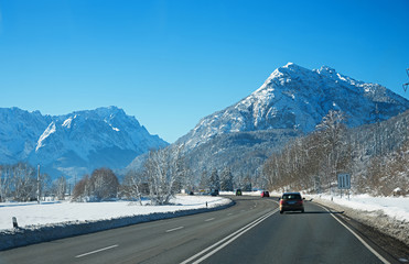 country road to garmisch with view to zugspitze mass in winter with traffic, bavarian alps