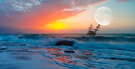 Sailing old ship in stormy sea in the background dramatic sunset and full moon 
