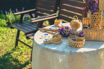 purple flower, candle, wicker basket decorating on table in garden