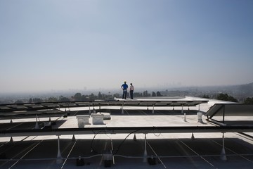 Maintenance Workers Near Solar Panels On Rooftop