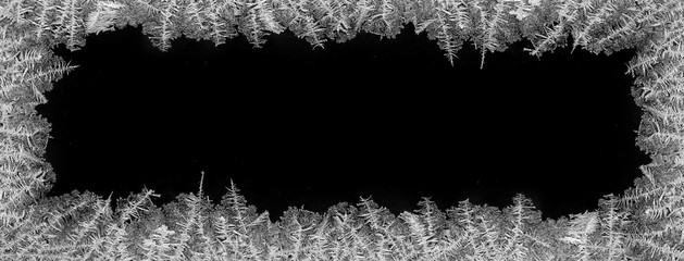 Decorative ice crystals on a window in form of a frame on black matte backgroundP
