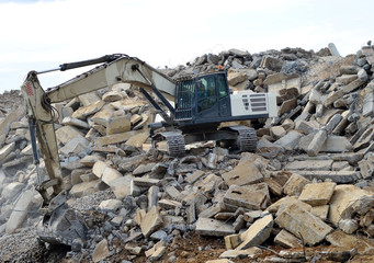 Salvaging and recycling building and construction materials. Industrial waste treatment plant. Excavator work at landfill with concrete demolition waste. Re-use concrete for new construction