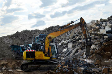 Obraz premium Salvaging and recycling building and construction materials. Excavator with hydraulic hammer work at landfill with concrete demolition waste. Reuse concrete for new construction
