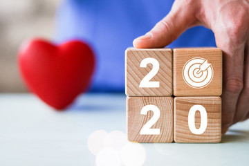 Hand holding wood block with New year 2020 and goal progress icon in healthcare.