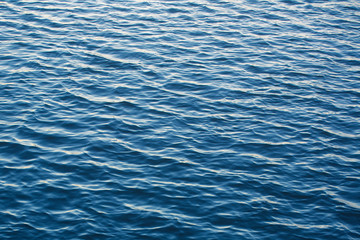 Infinite background of water waves in lake. Blue to black colors. Natural texture.