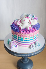 Colored cake with pink melted chocolate and white fondant rabbit.