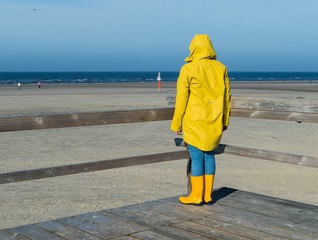 Junge Frau im Regenmantel auf Plattform Strand 