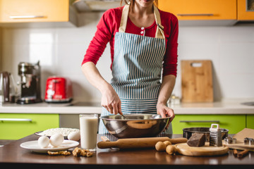 Cook housewife making cookies at home on colourful kitchen. Woman stirs the dough at a table with ingredients