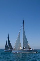 Fototapeta na wymiar Sailboats Racing In The Blue Ocean Against Sky