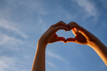 palms form a heart shape. heart on sky background. hands on sky background.